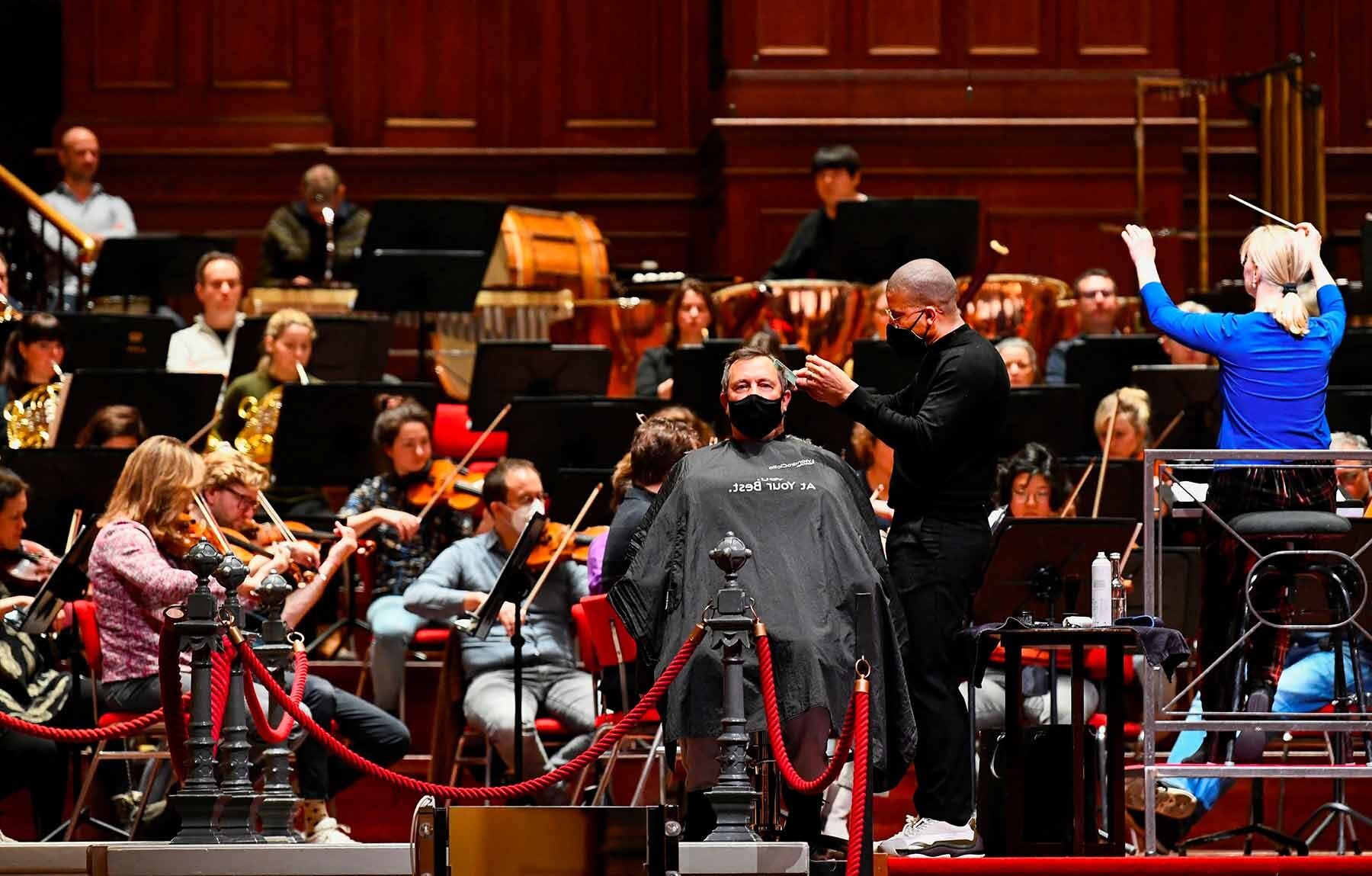 Un cliente si fa tagliare i capelli durante un concerto ad Amsterdam - foto di Piroschka van de Wouw/REUTERS